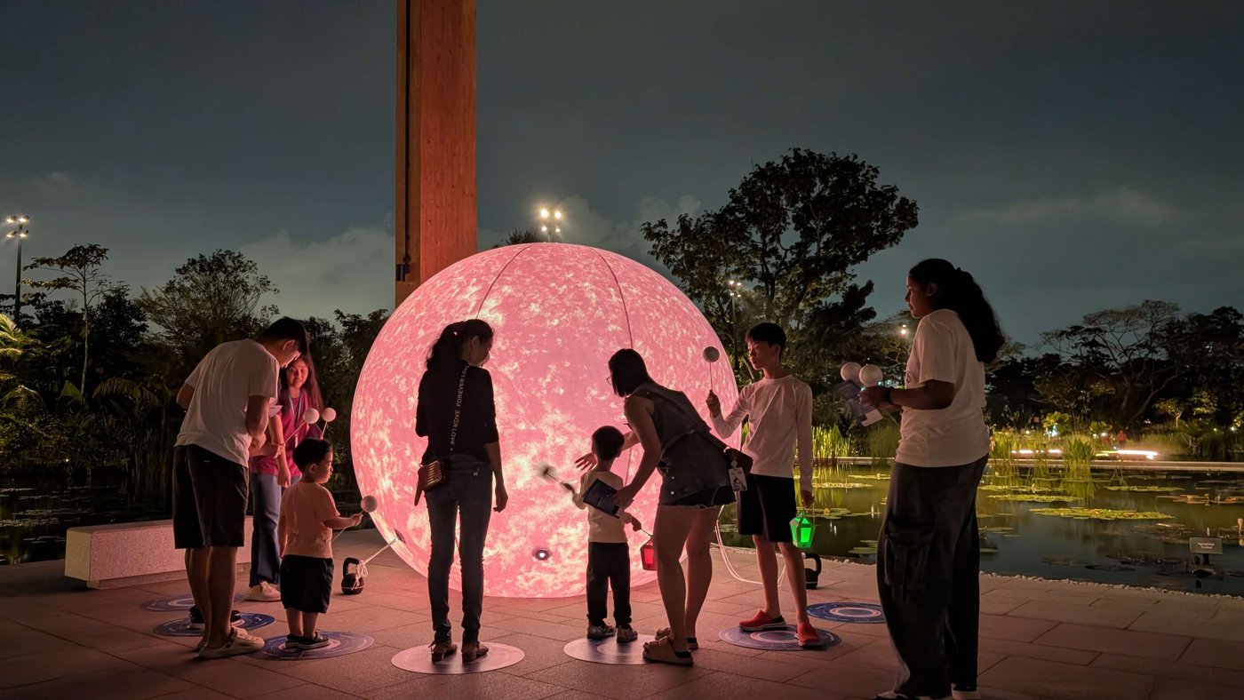 Families around a glowing moon globe on the Celestial Trail at Science Centre Singapore